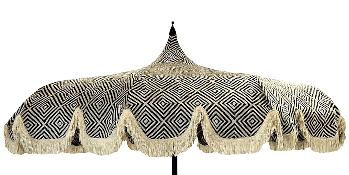 Frange Parasol rond à toile noire et blanche à motif géométrique en losanges, avec sommet pointu, bordures ondulées et longues franges beige, monté sur un mât sombre, photographié sur fond neutre.