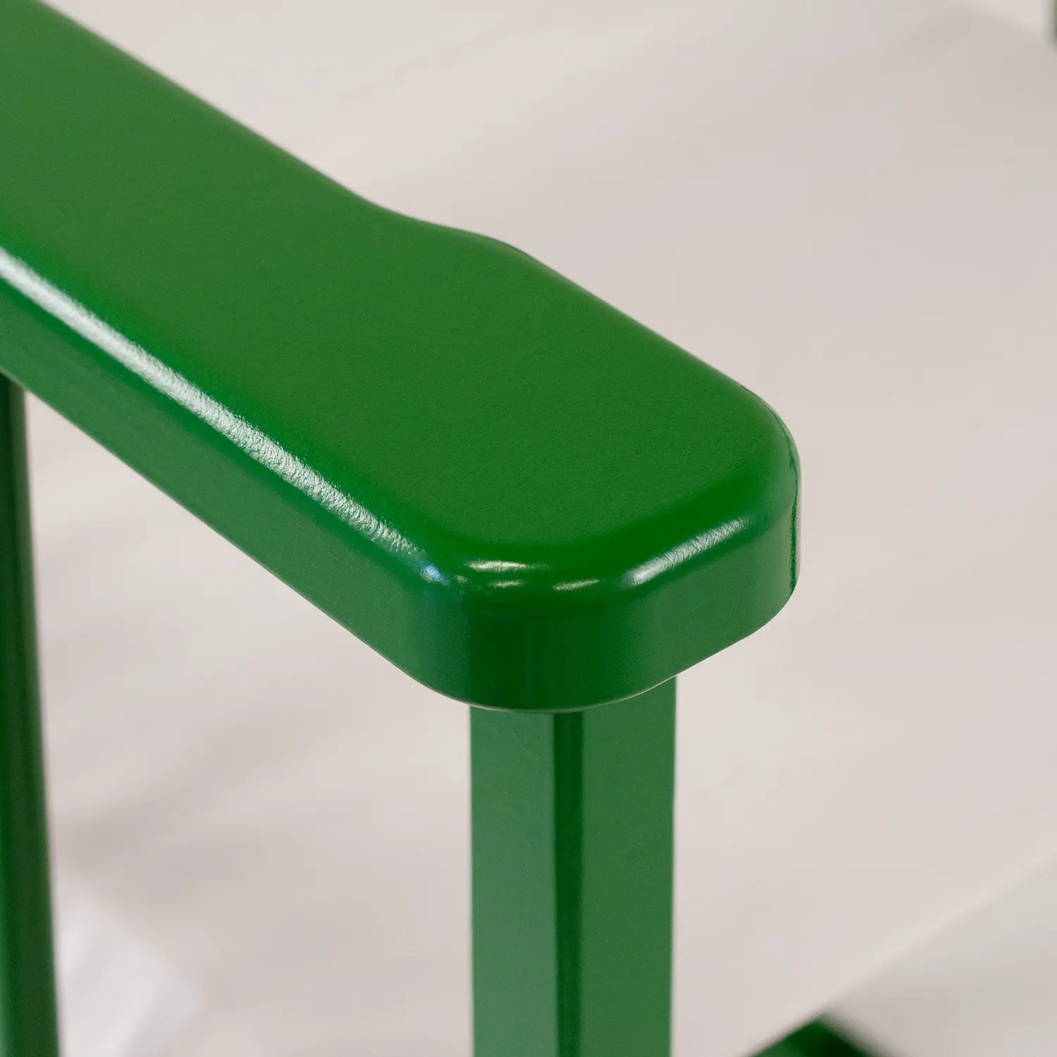 Gros plan de l’accoudoir vert forêt d’un fauteuil, avec la toile écrue de l’assise en arrière-plan.